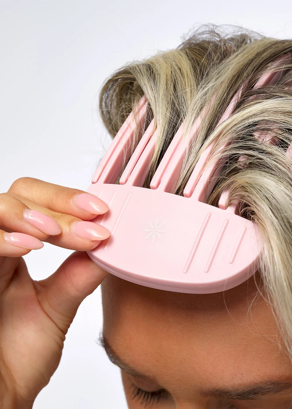 Model using a pink Brushworks hair tool in blonde hair