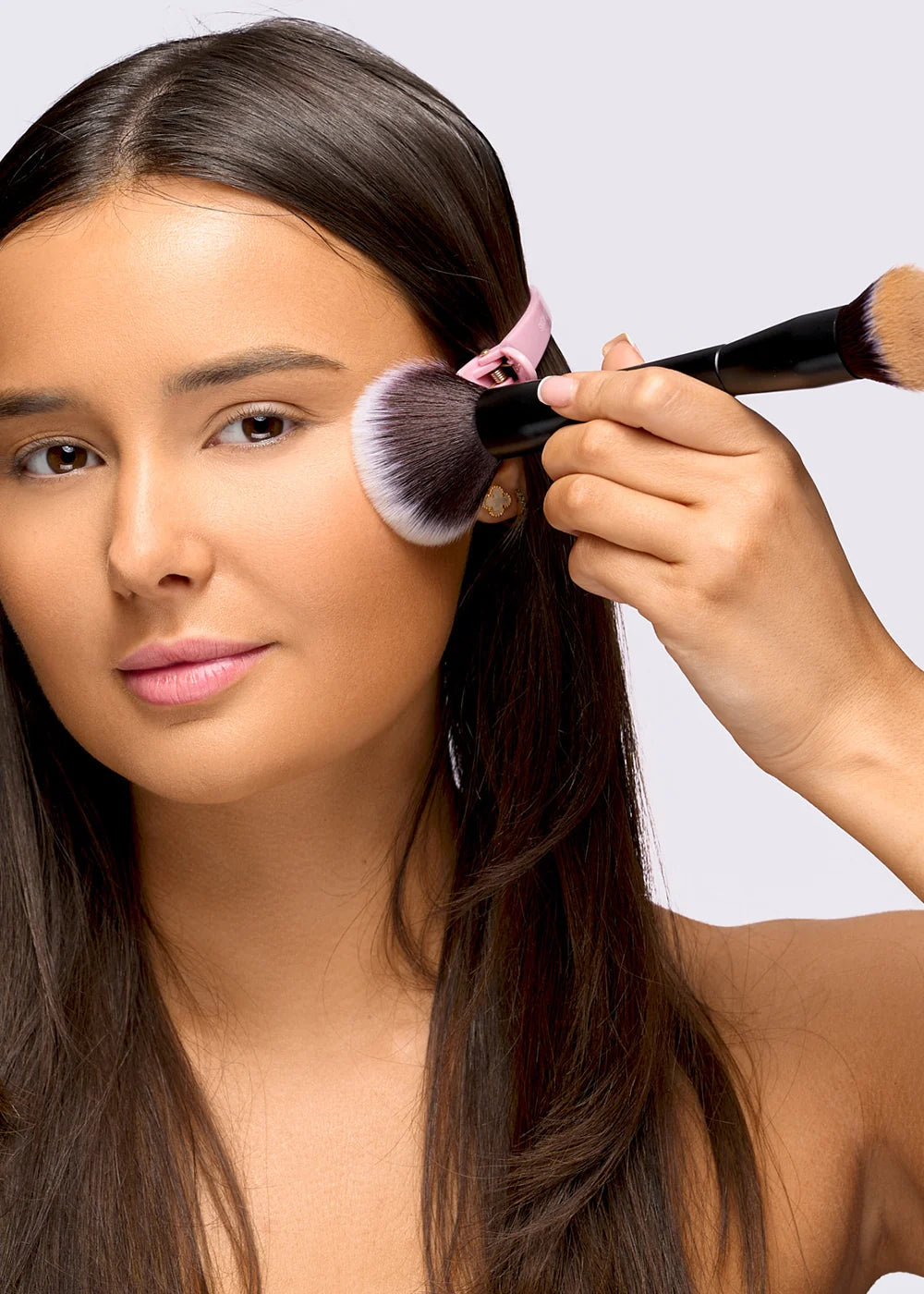 Model applying complexion makeup with a black Brushworks face brush
