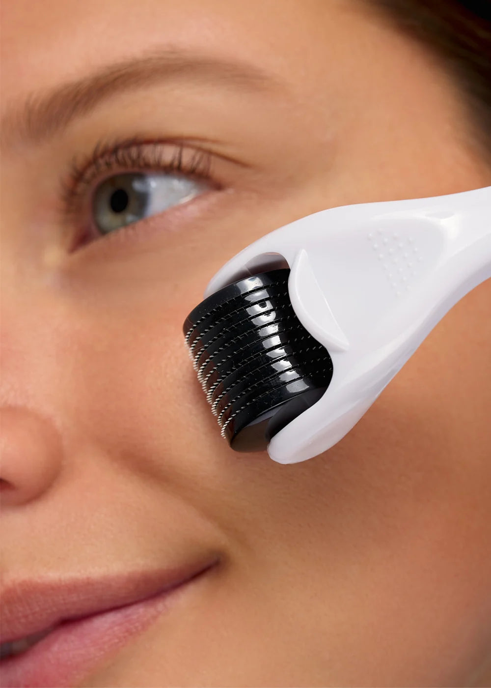 Close-up of a white Brushworks facial roller being used on a cheek